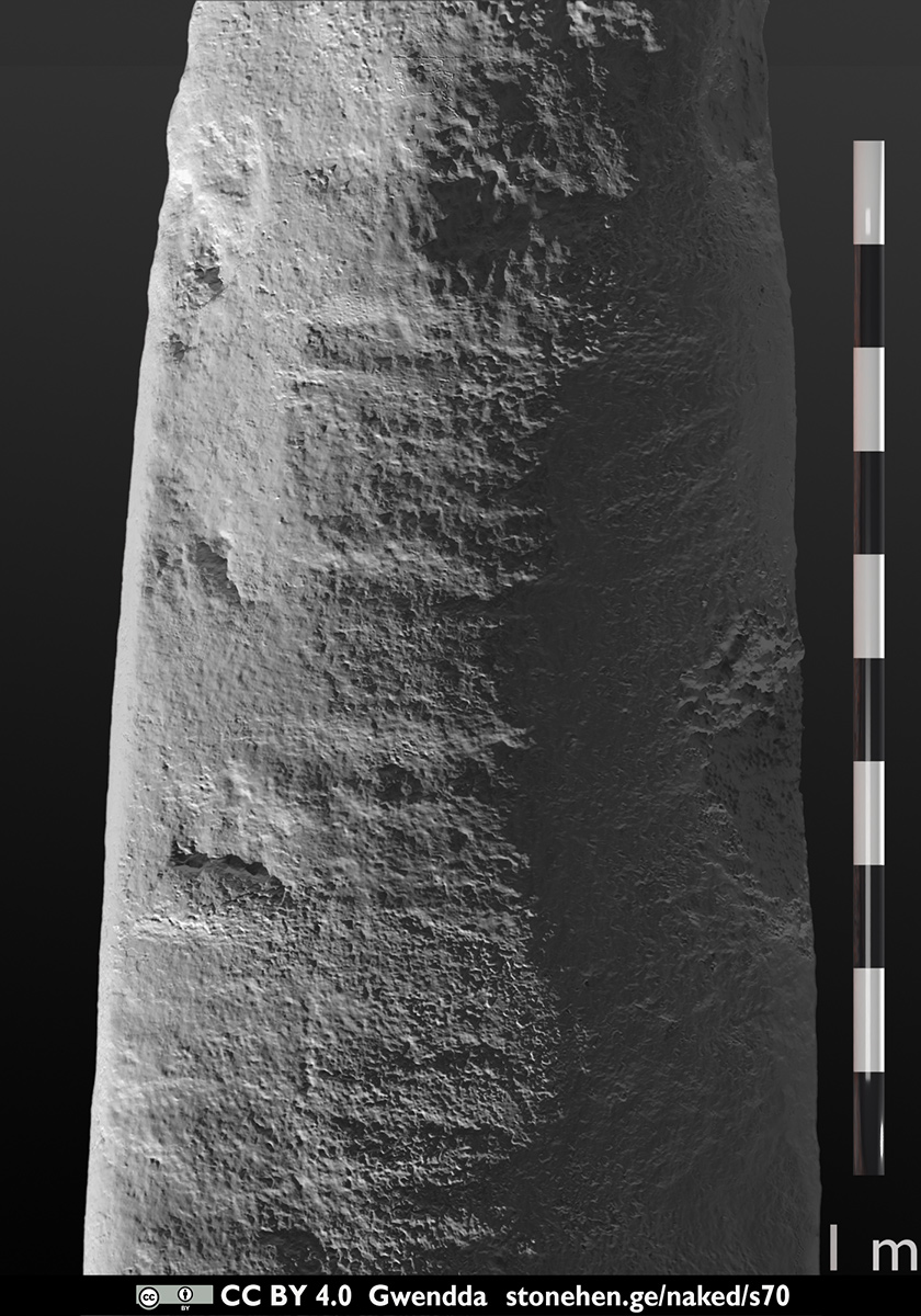 Stone 70, outer face at closer framing, raking light from the lower left at 3.0 degrees, with rule and hand for scale